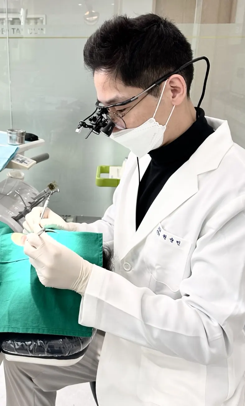 확대경을 착용한 권순민 대표원장이 진료실에서 환자를 진료하는 모습